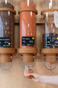A woman is filling red lentils in an unpackaged shop. A woman is filling red lentils in an unpackaged shop.